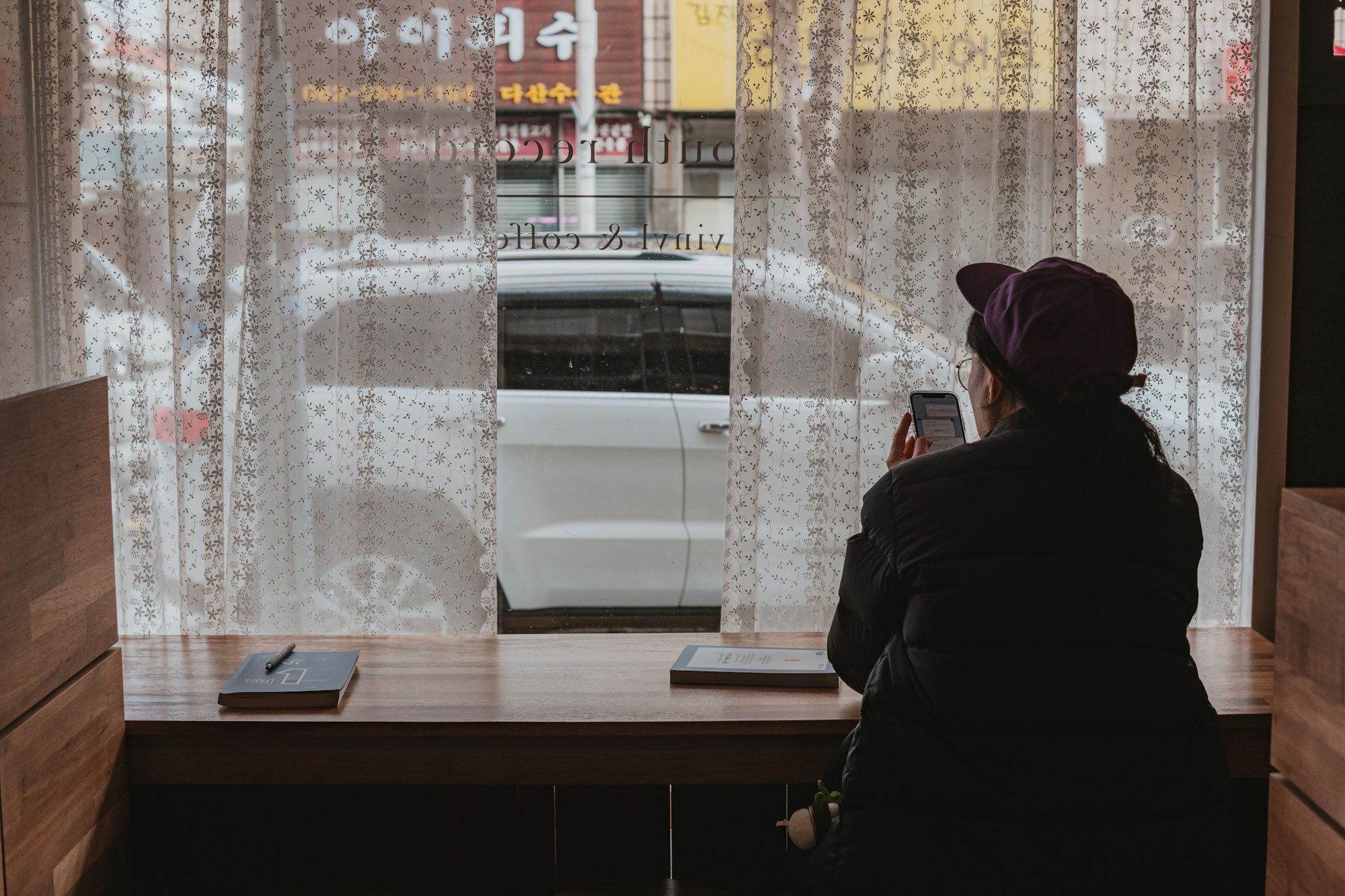 Looking at a phone through lace curtains. Photo by Seungmin Yoon on Unsplash.